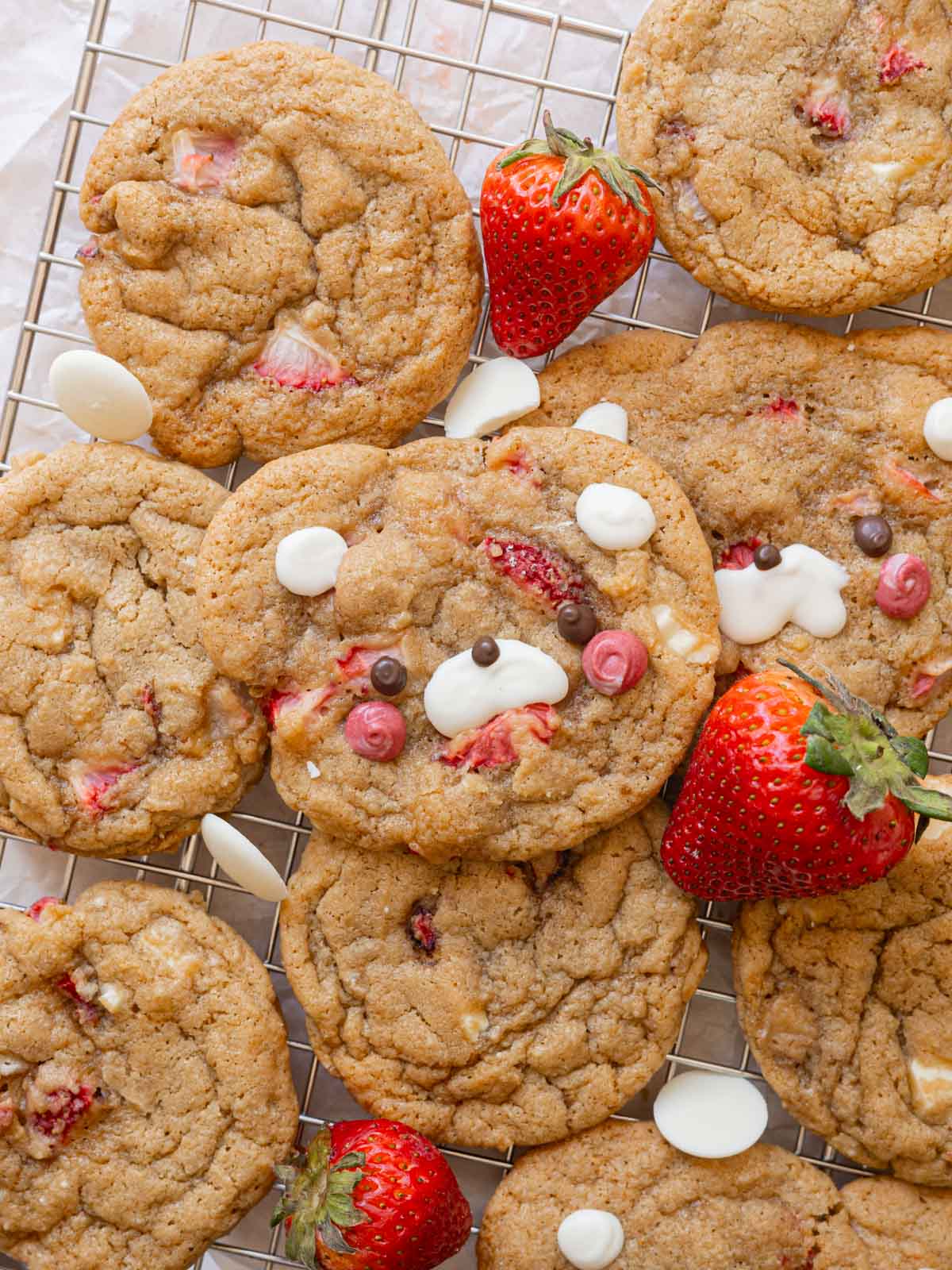 White chocolate strawberry cookies layered on top of one another on a wire rack.