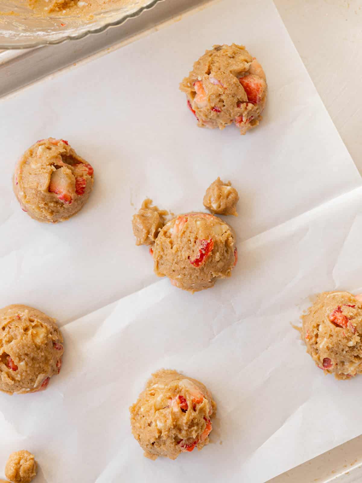 Strawberry cookie dough balls on lined baking tray, ready for the oven!