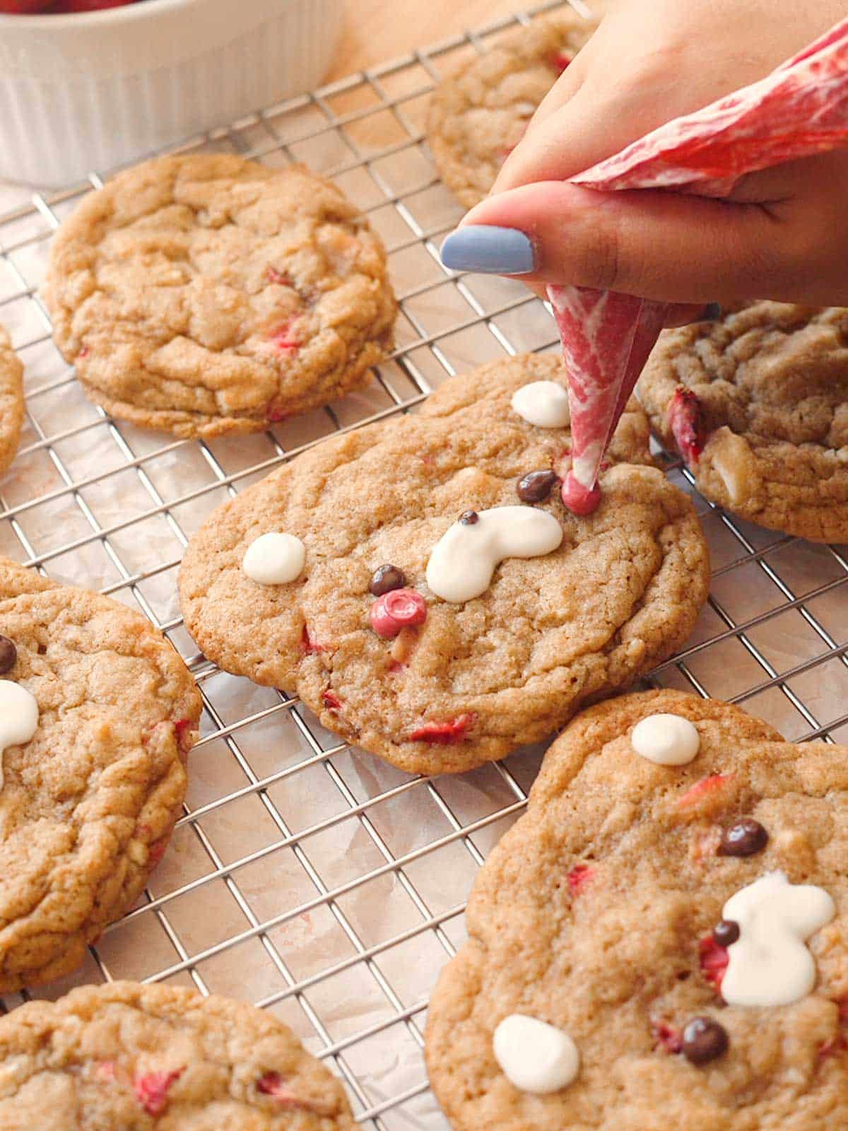 Adding blush to bear cookie with red-dyed chocolate.