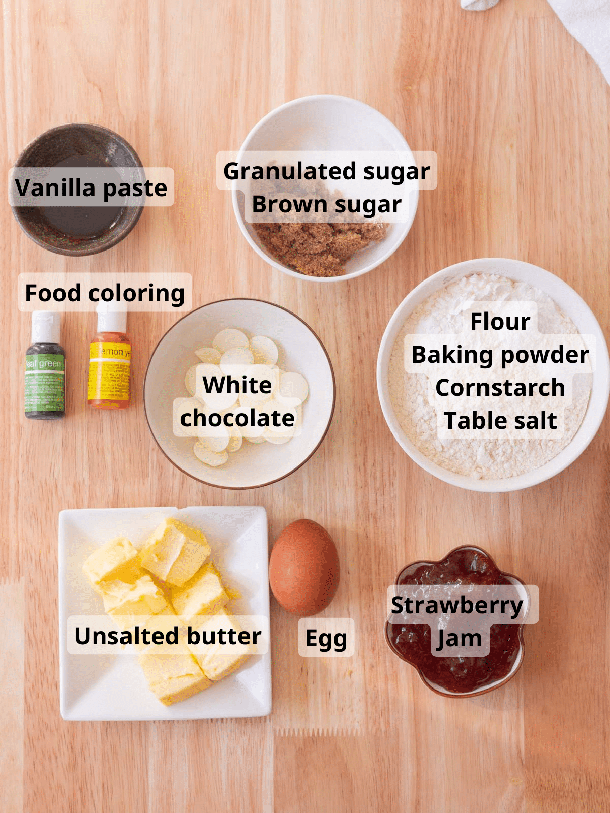 Strawberry thumbprint cookie ingredients labeled on a light wooden background.