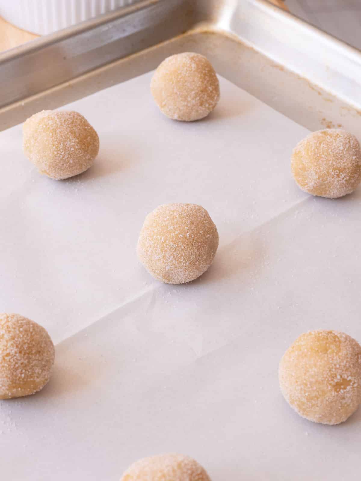 Rolled out cookie dough balls on lined baking tray.