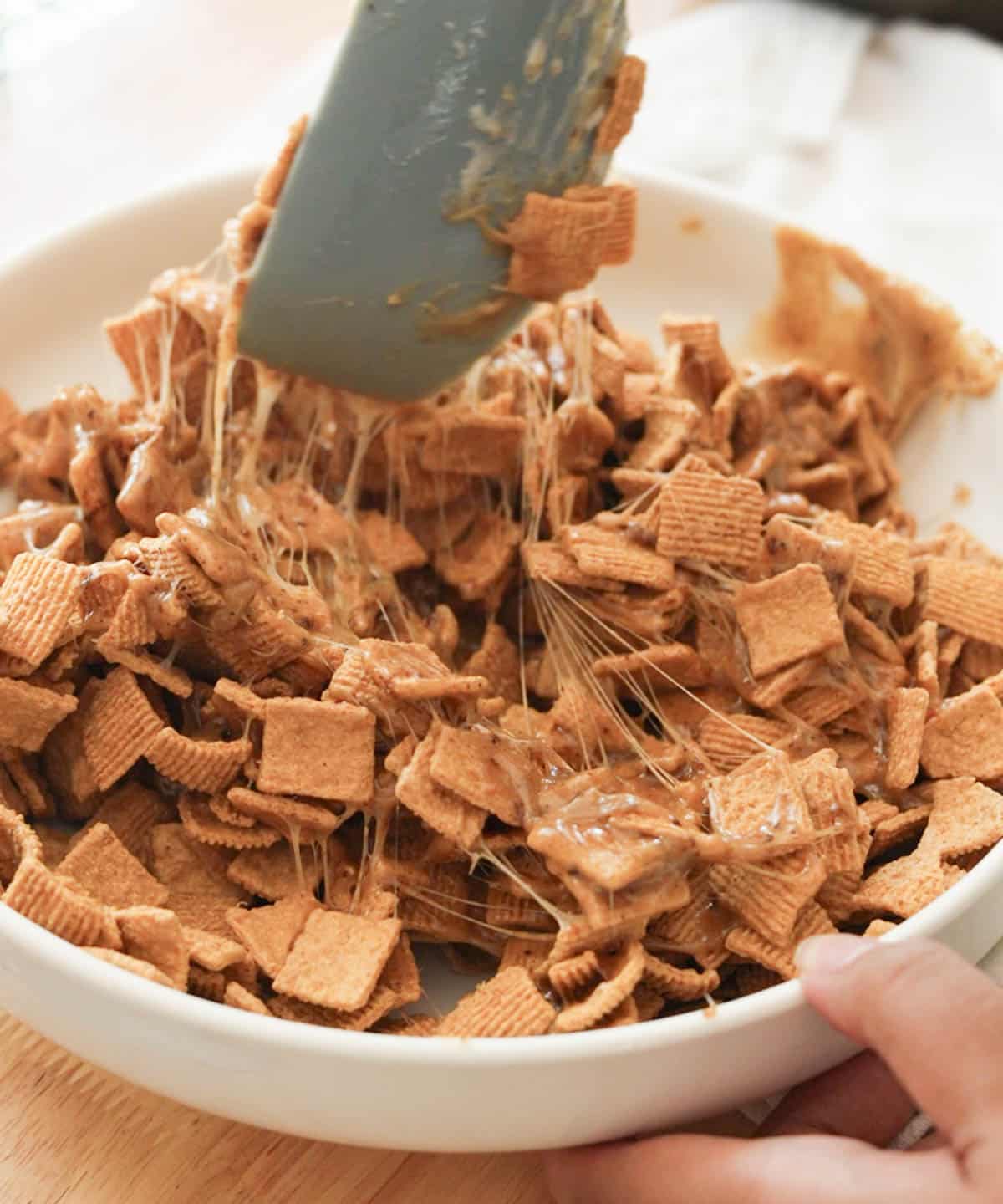 Stirring Golden Grahams with toasted marshmallow mixture.