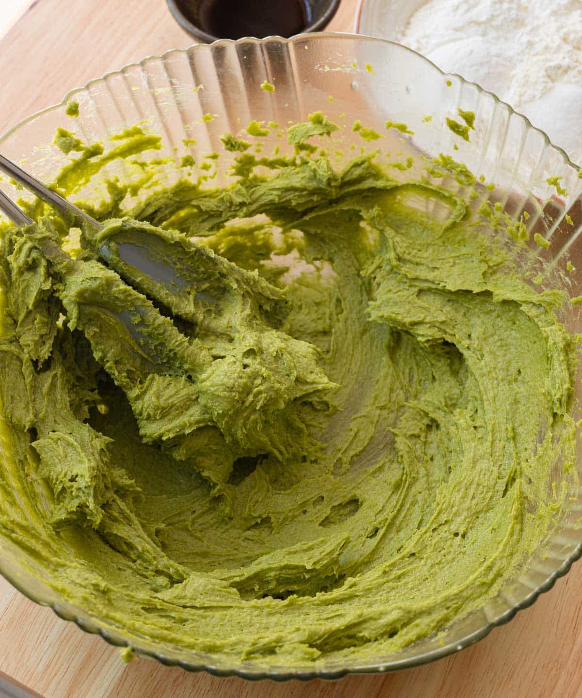 Butter, sugar, and matcha whipped in a glass mixing bowl.