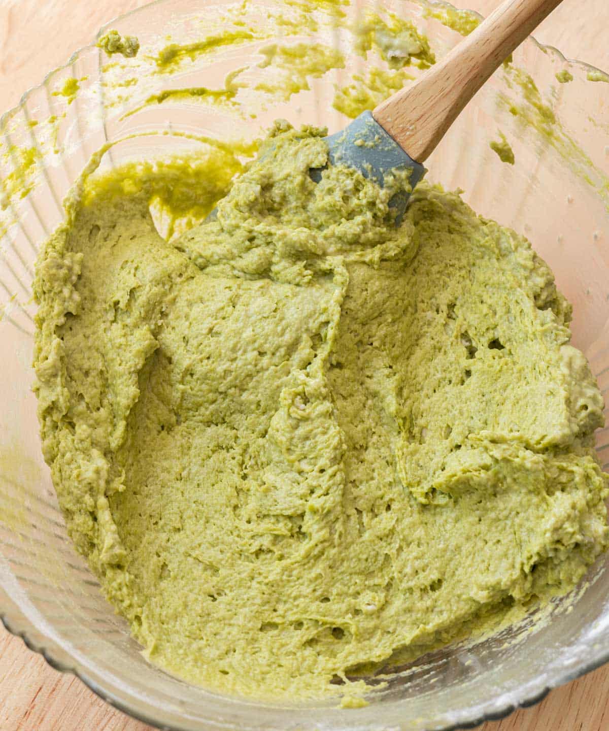 Matcha cake batter in glass mixing bowl.