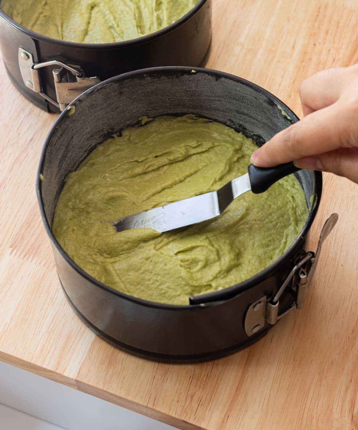 Spreading matcha cake batter into a 6-inch springform pan.