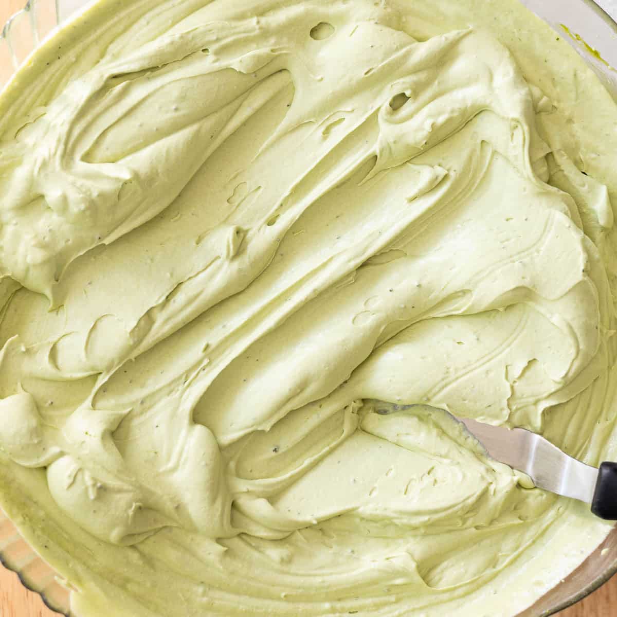 Stabilized matcha whipped cream in a glass mixing bowl.