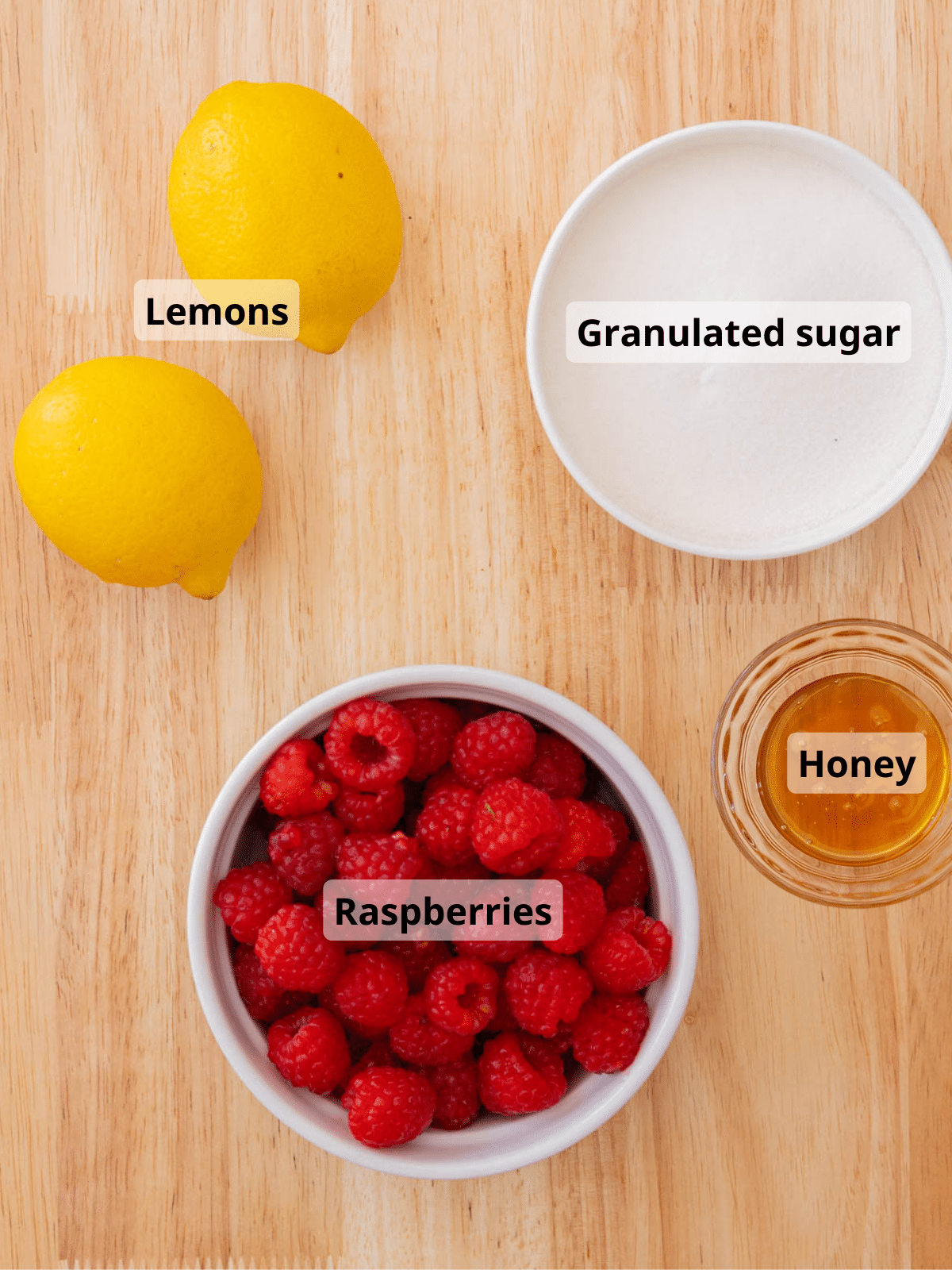 Raspberry jam labeled ingredients laid out on a wooden table.