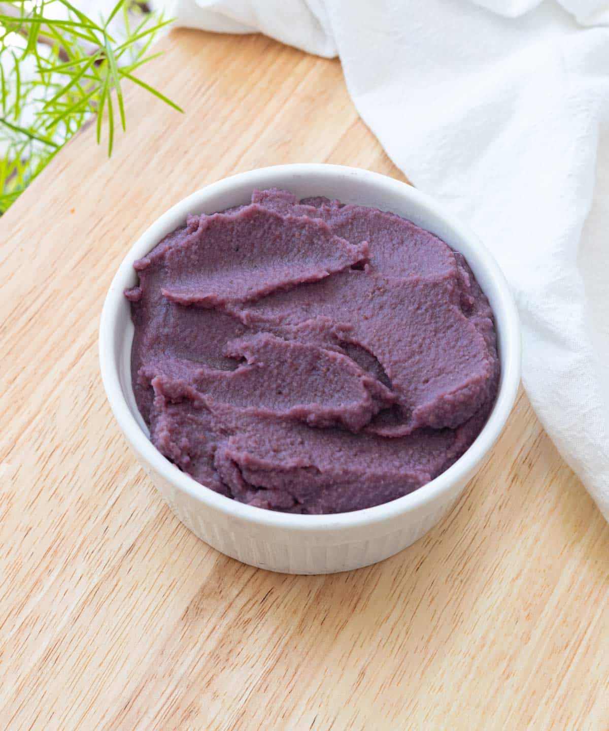 Rehydrated ube powder in a white ramekin on top of a wooden kitchen island.