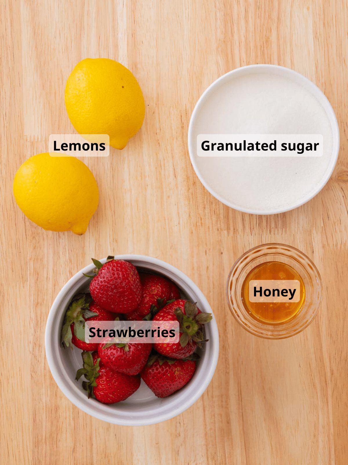 Strawberry jam labeled ingredients laid out on a wooden table.