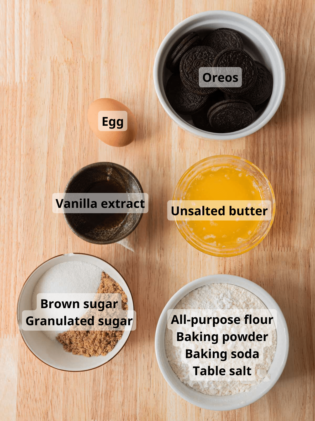 Oreo stuffed cookie ingredients laid out on a wooden table, with labels for each ingredient.