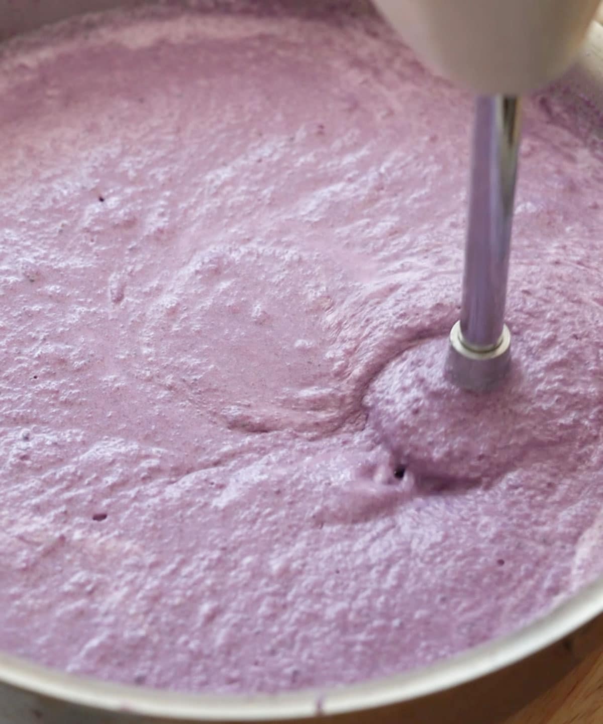 Immersion blending grated ube, evaporated milk, and coconut milk.