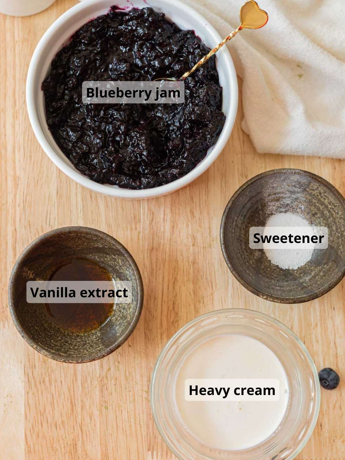 Blueberry cold foam ingredients laid out on a wooden table, with labels for each ingredient.