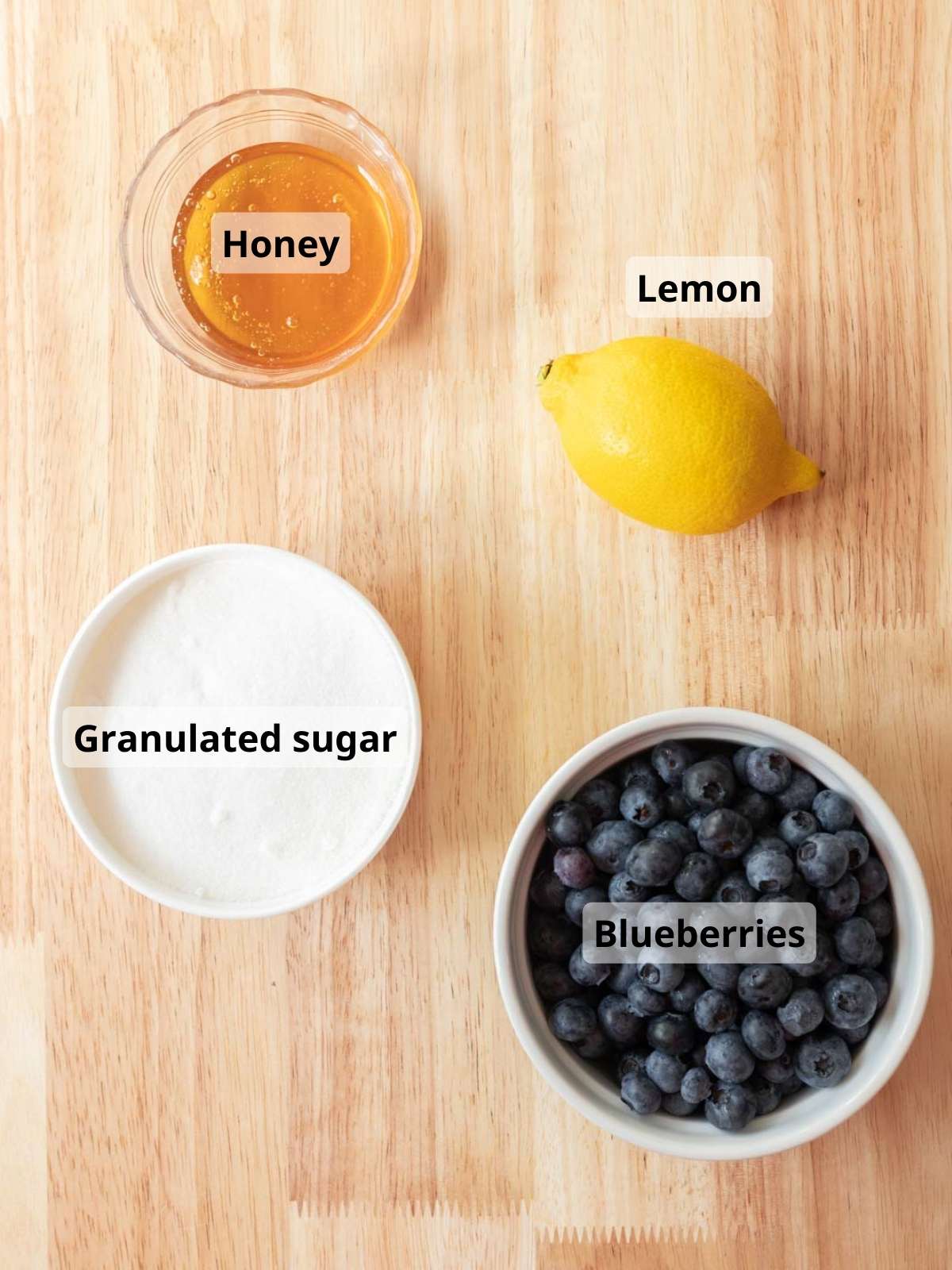 Blueberry jam labeled ingredients laid out on a wooden table.