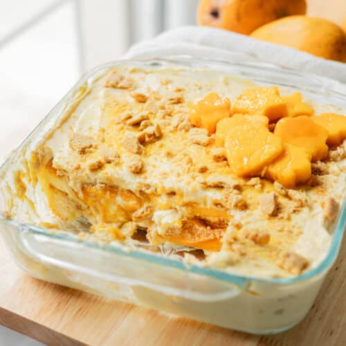 Filipino mango float in glass baking dish with a large slice taken out of it.