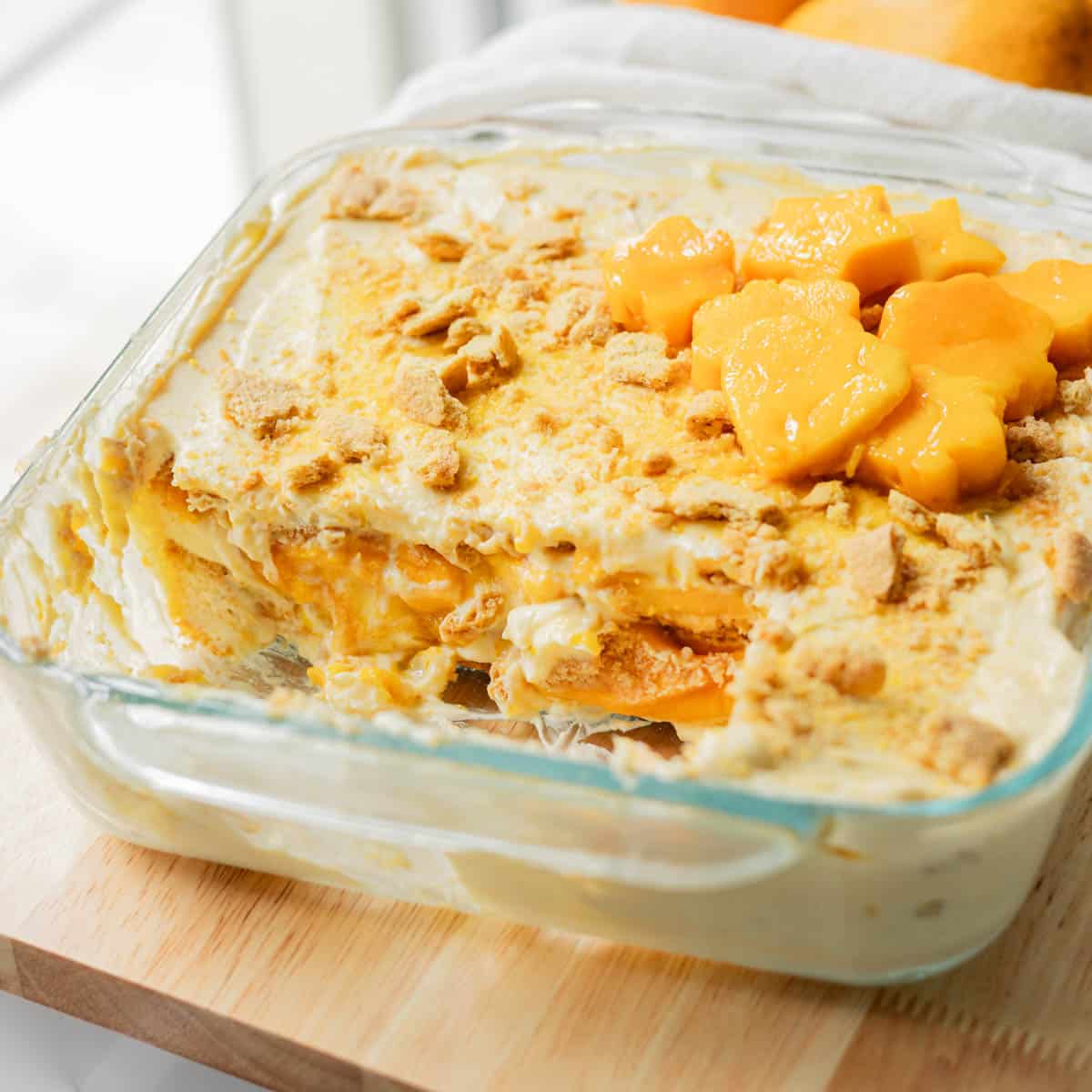 Filipino mango float in glass baking dish with a large slice taken out of it.