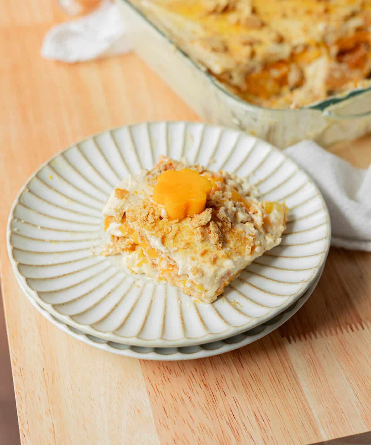 Triple mango float slice on a white fluted plate.