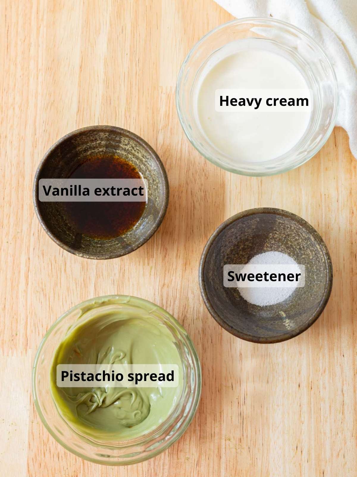 Pistachio foam ingredients laid out on a wooden table, with labels for each ingredient.