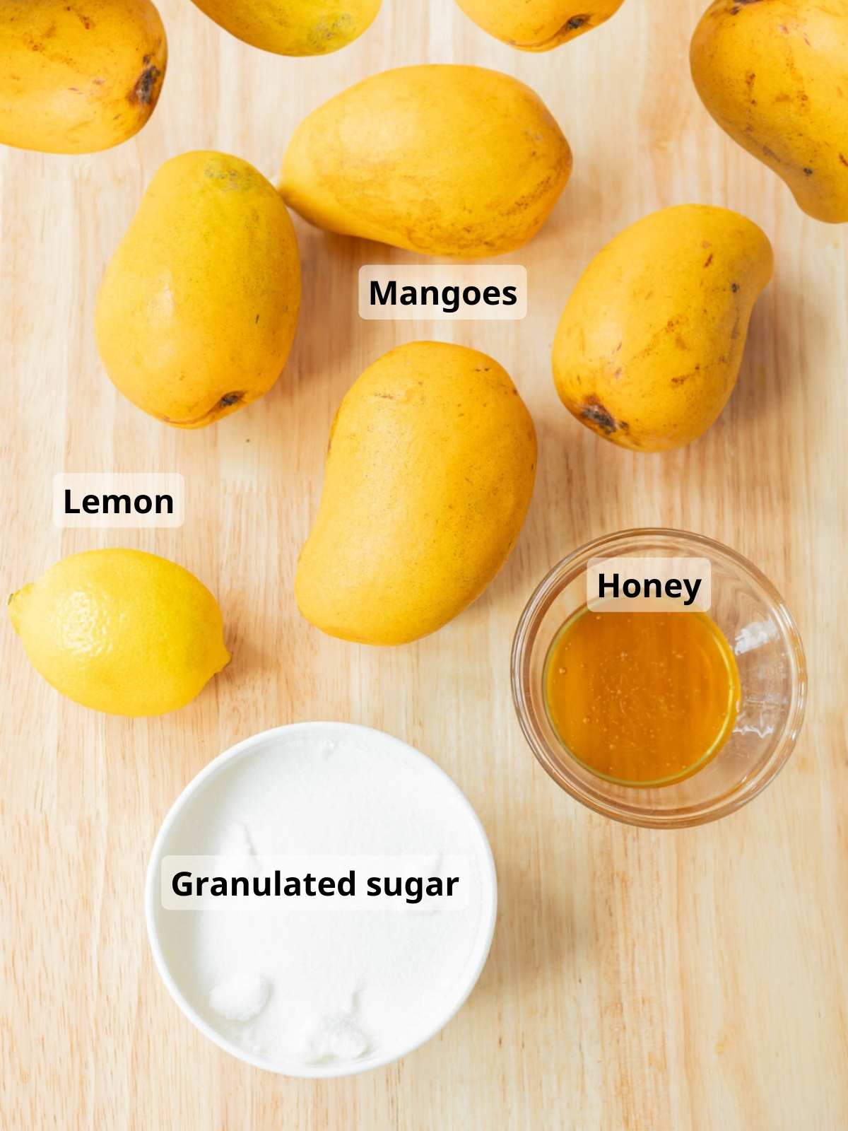 Mango jam labeled ingredients laid out on a wooden table.