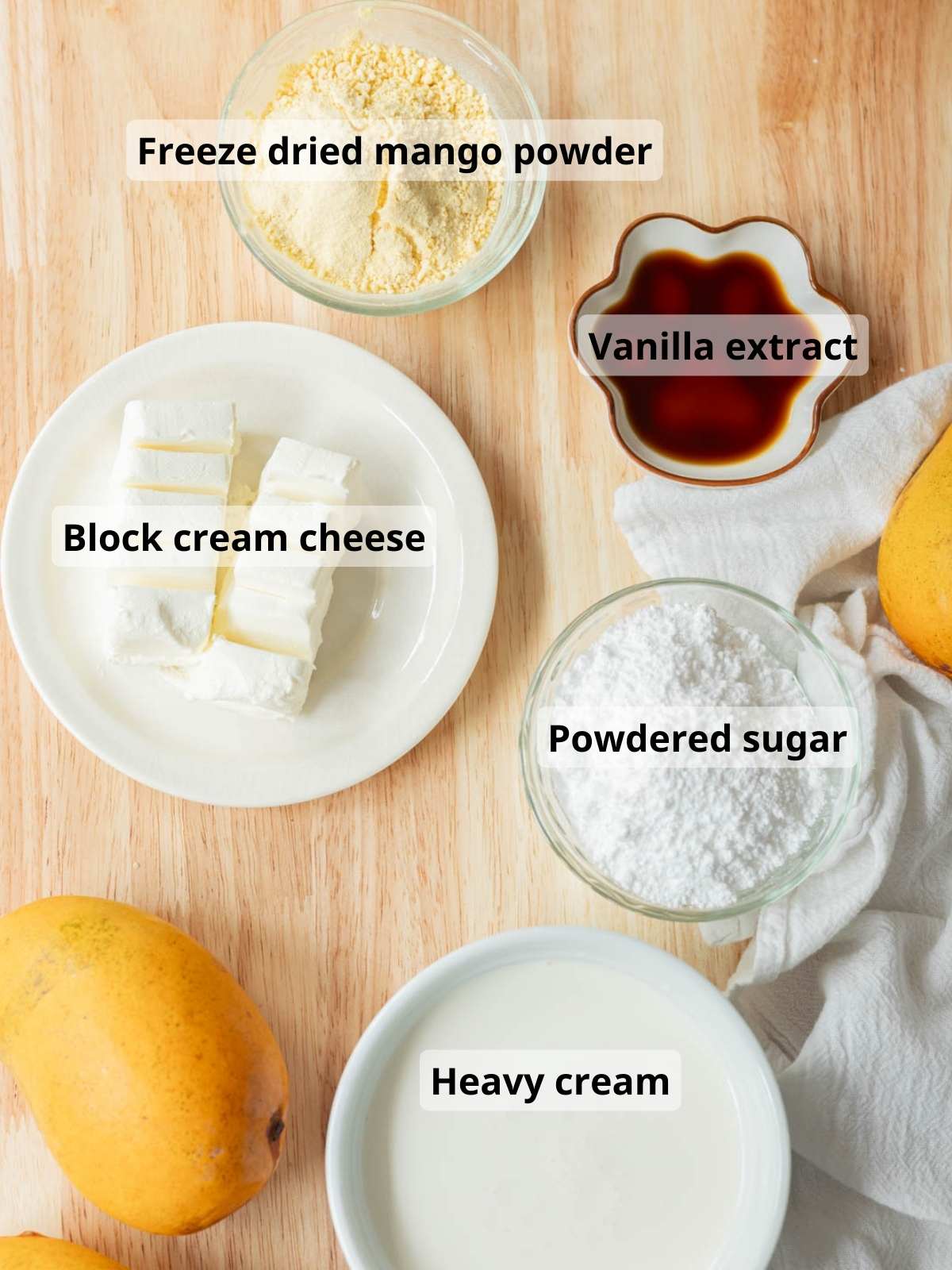 Stabilized freeze dried mango whipped cream frosting labeled ingredients laid out on a wooden table.