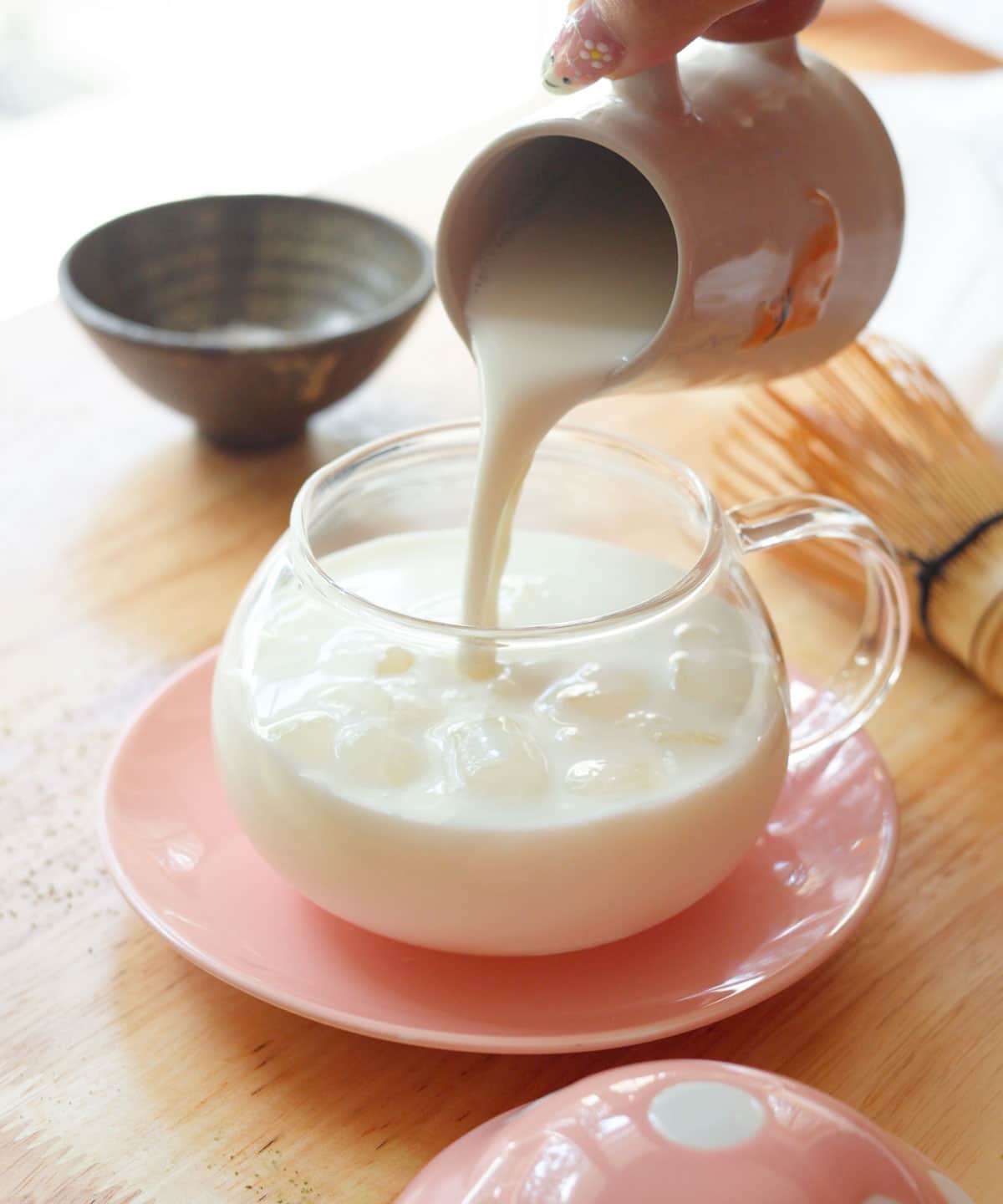 Pouring milk into a glass cup with ice.