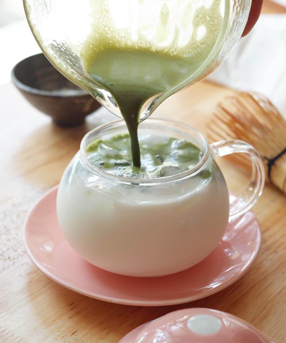 Pouring whisked matcha into glass of ice milk.