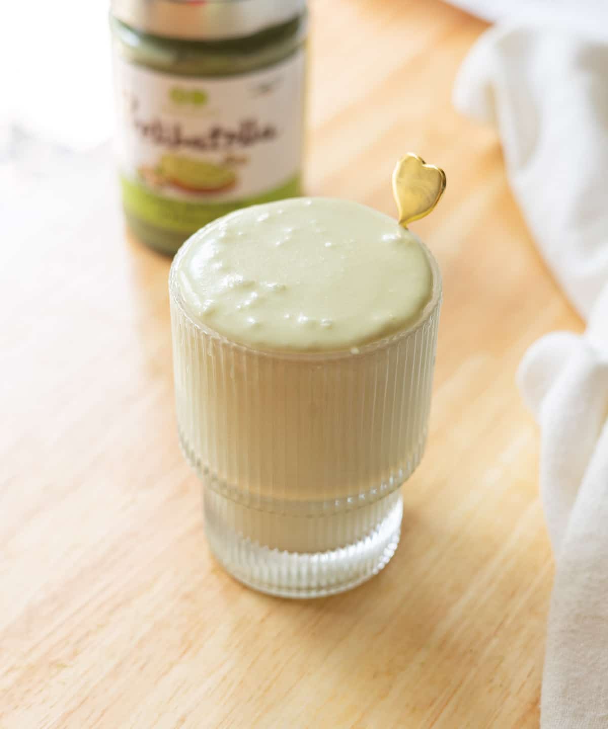 Thick, fluffy pistachio cold foam in a fluted glass cup.