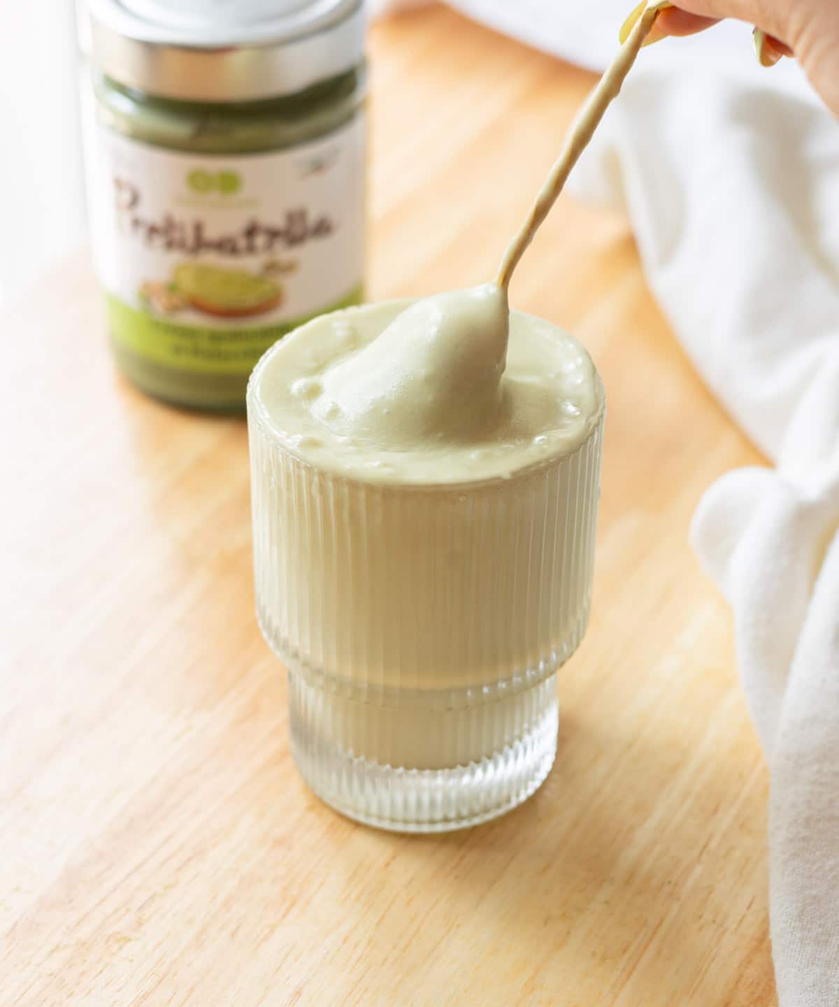 Thick, fluffy pistachio cold foam in a fluted glass cup.