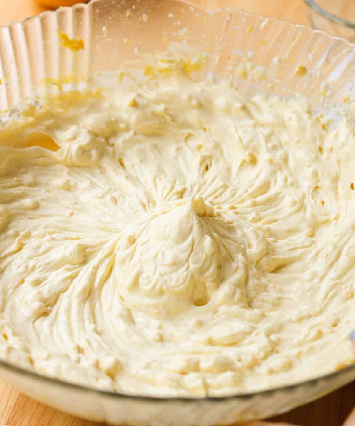 Stiff peak mango whipped cream frosting in a glass bowl.