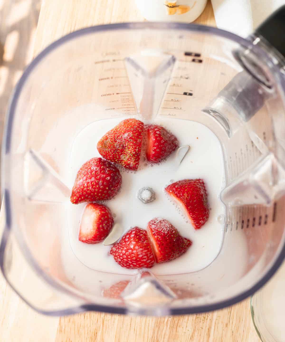 Birds eye view of strawberry cold foam ingredients in a blender.