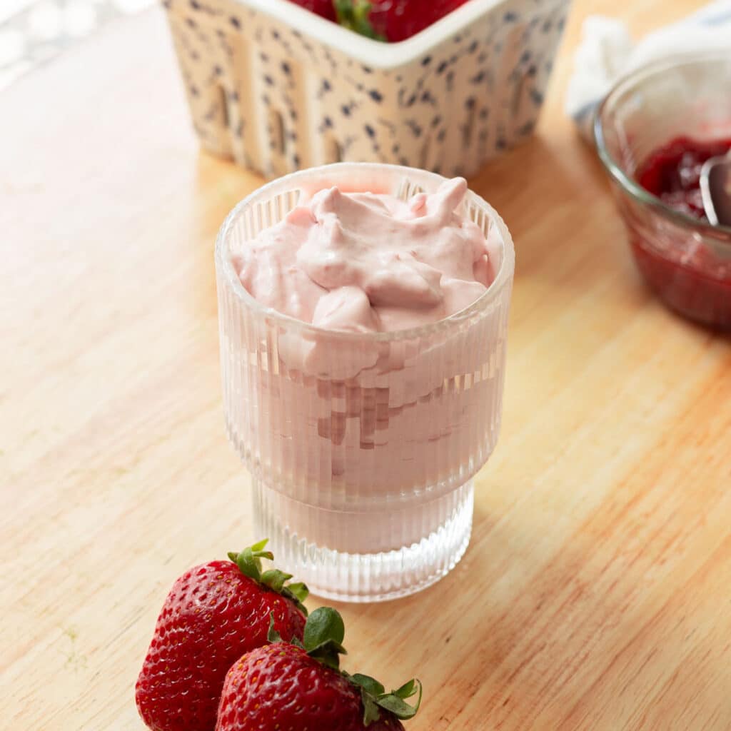 Strawberry cold foam in a fluted glass cup, on a wooden table.