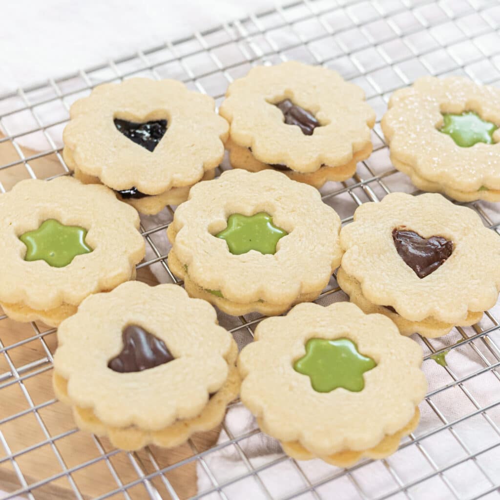 Cute cut-out linzer cookies filled with matcha ganache, chocolate ganache, or jam.
