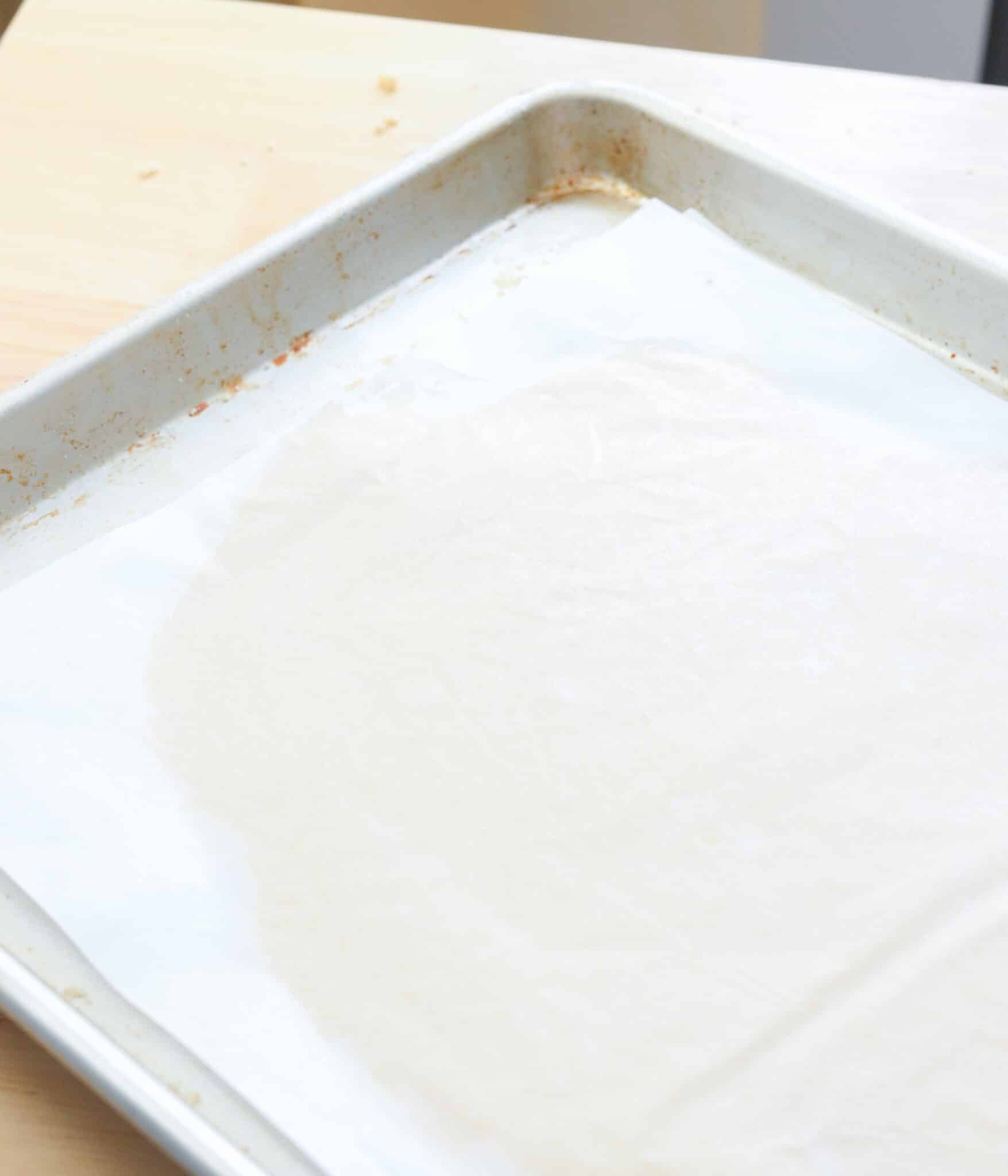 Rolled out linzer cookie dough between two pieces of parchment paper.
