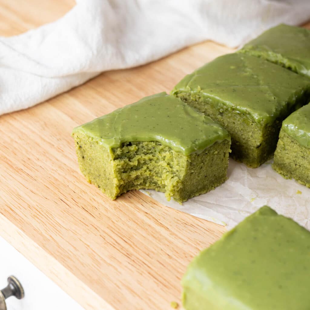 Cakey matcha mochi brownies with a bite mark taken out of it.