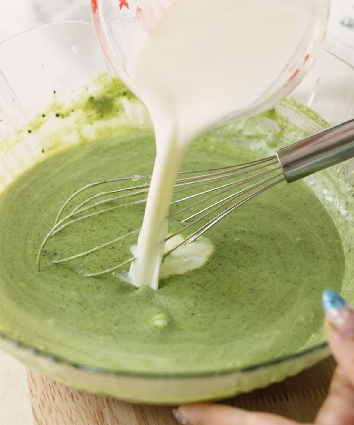 Pouring milk into matcha mochi brownie batter.