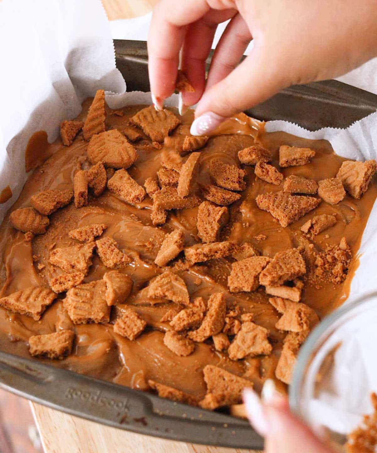 Topping blondie batter with crushed Biscoff cookies.