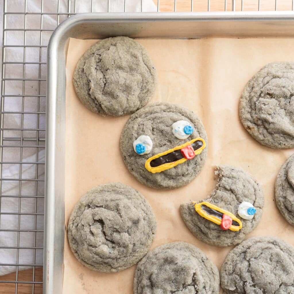 Black sesame cookies decorated as rocks on a lined baking sheet.