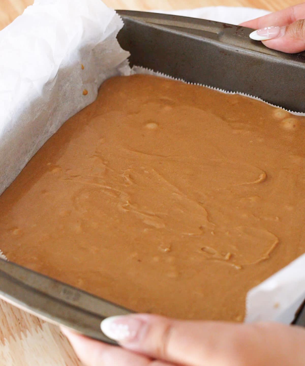 Holding the lined baking pan with blondie batter, about to be transferred to the oven.