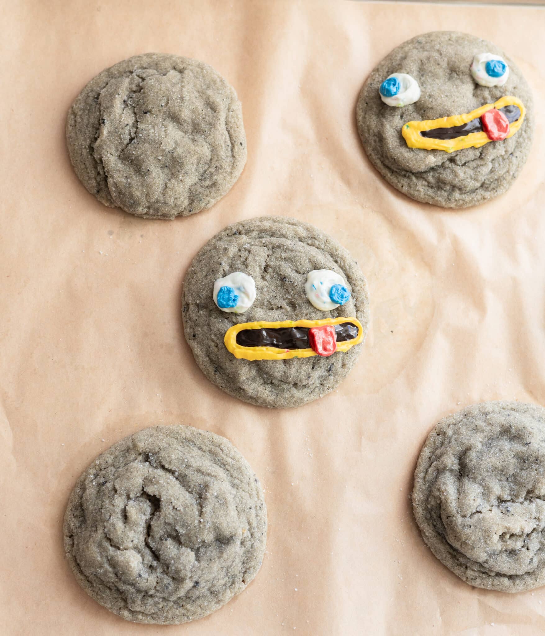 Black sesame cookies decorated as rocks on a lined baking sheet.