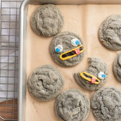 Black sesame cookies decorated as rocks on a lined baking sheet.