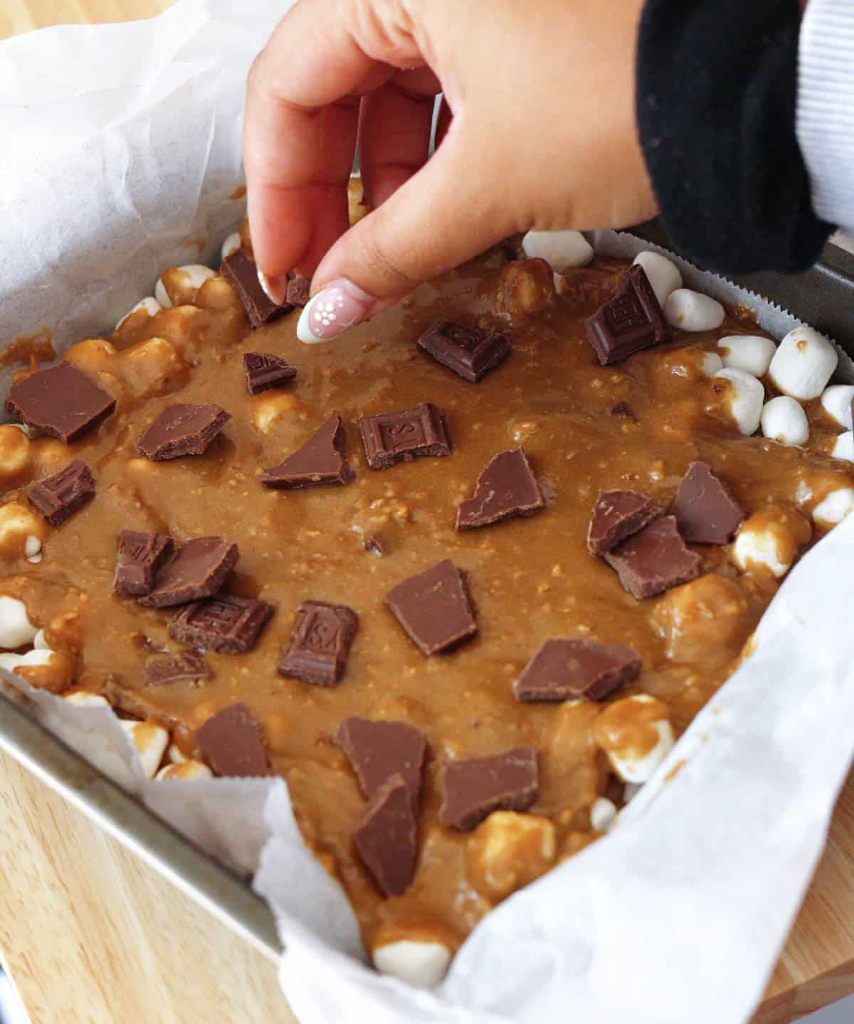 Topping blondie batter with chopped chocolate before baking.