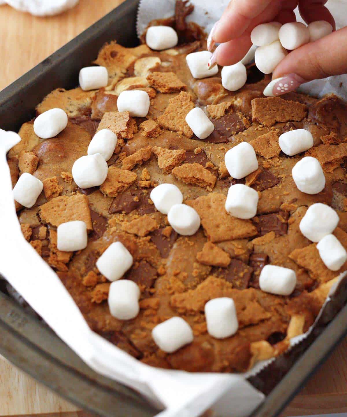 Topping mostly baked blondies with mini marshmallows.