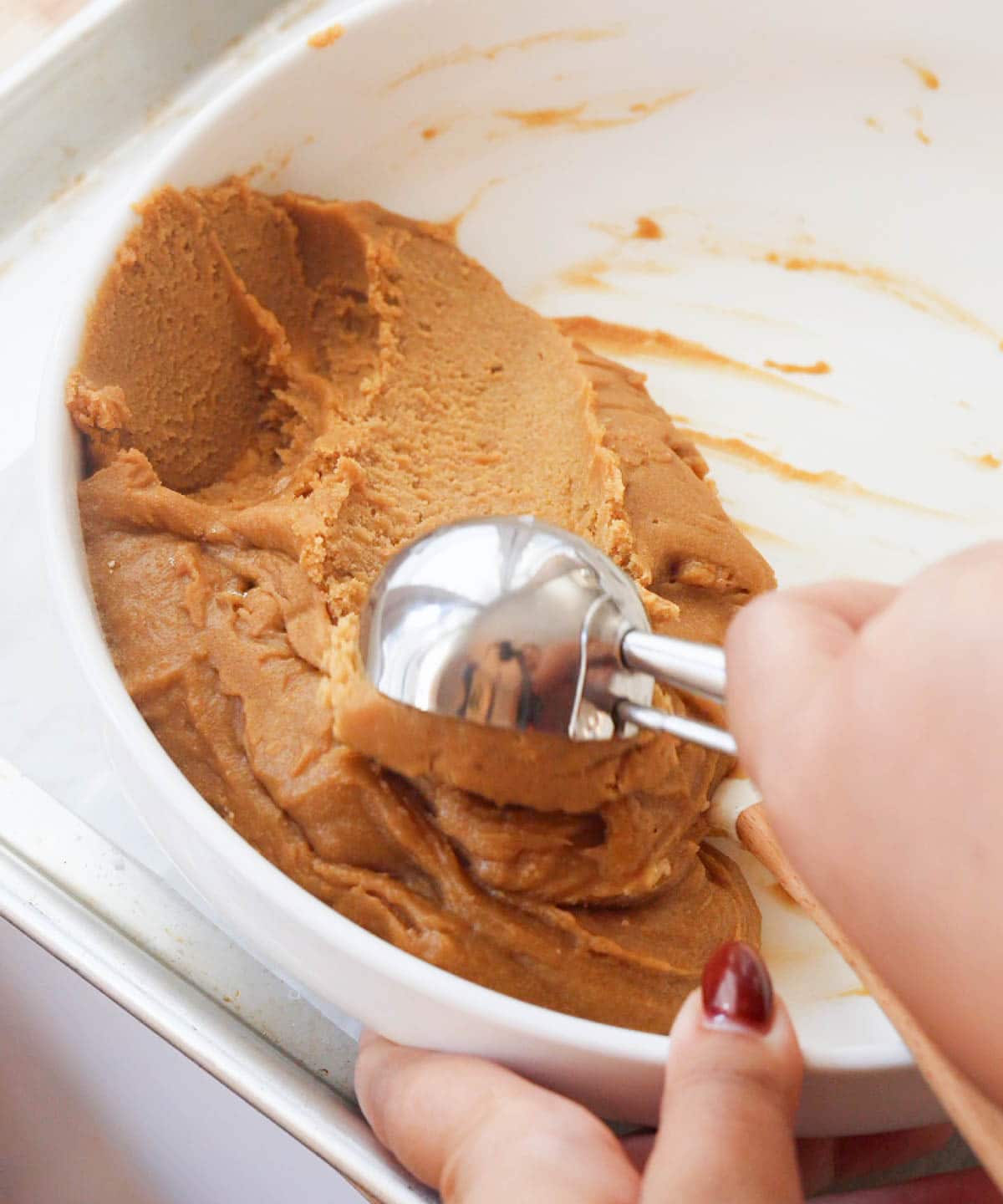 Using a medium scoop to scoop cookies.