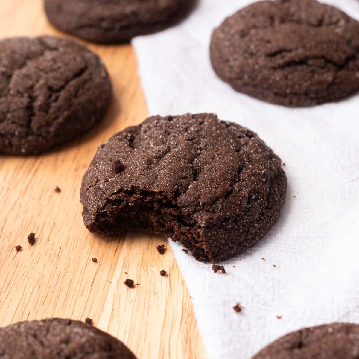 Chocolate sugar cookies on wooden table with white linen.