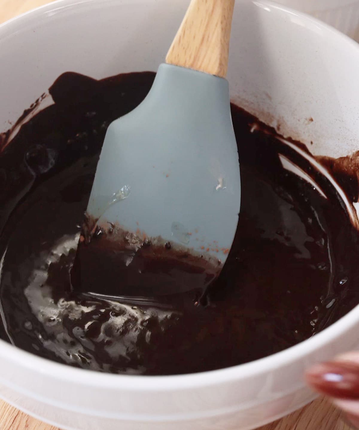 Cocoa powder and melted butter fully mixed in white bowl.