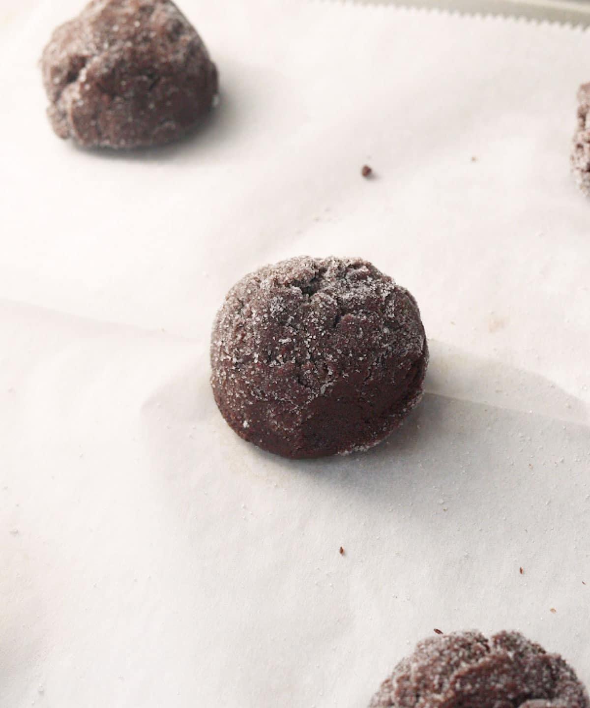 Rolled chocolate sugar cookie dough balls ready to be baked.