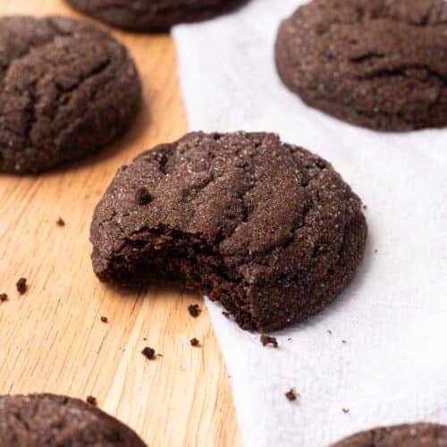 Chocolate sugar cookies on wooden table with white linen.