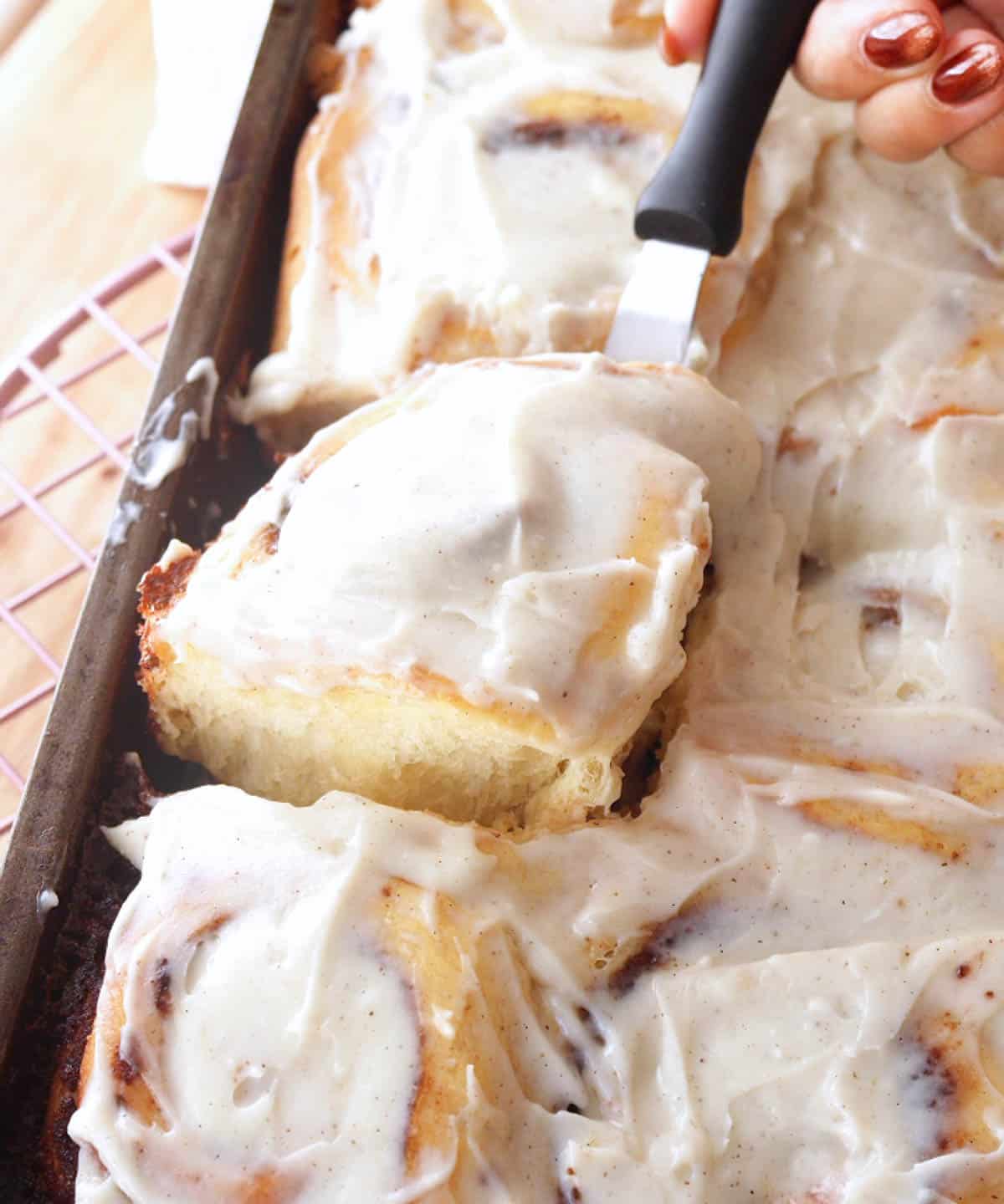 Taking cinnamon roll out of baking pan.