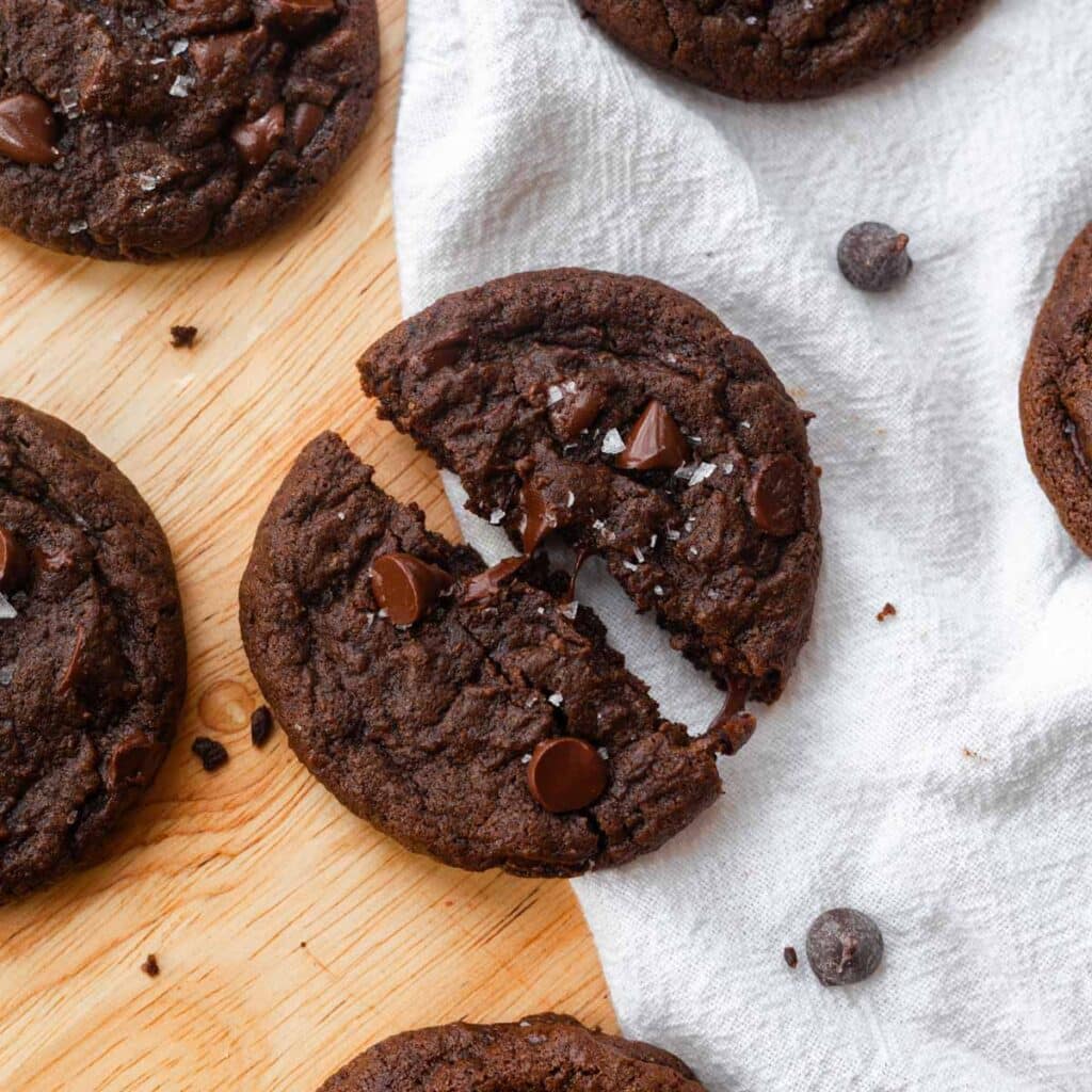 Double chocolate chip cookies on a wooden table with white linen.