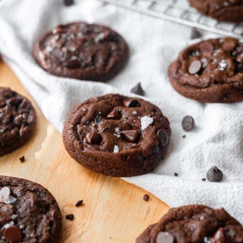 Double chocolate chip cookies on a wooden table with white linen.