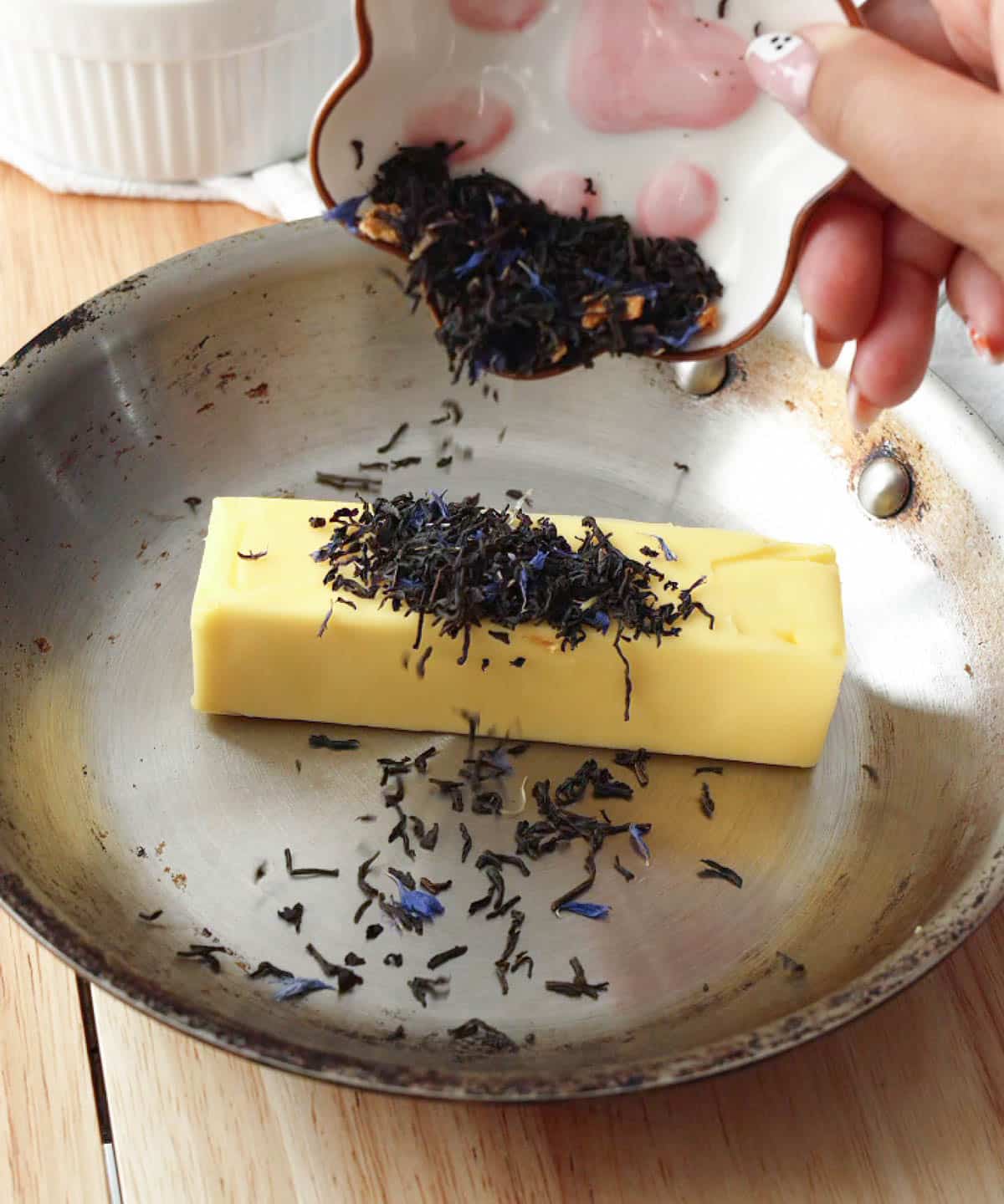 Adding earl grey tea leaves and butter to a pan to melt.